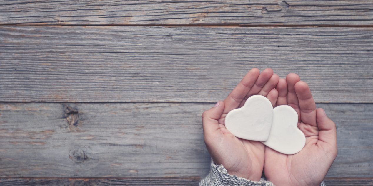 Woman holding two white love hearts.