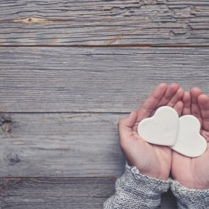 Woman holding two white love hearts.