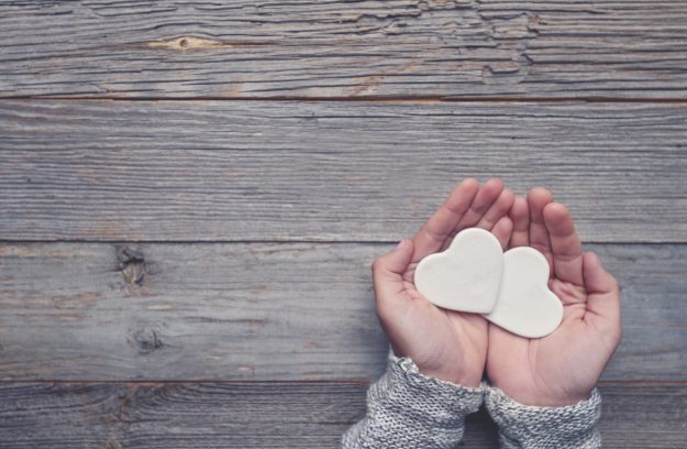 Woman holding two white love hearts.