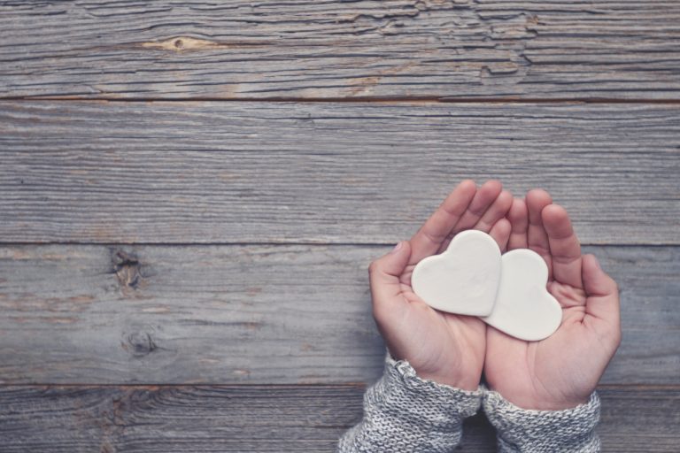 Woman holding two white love hearts.