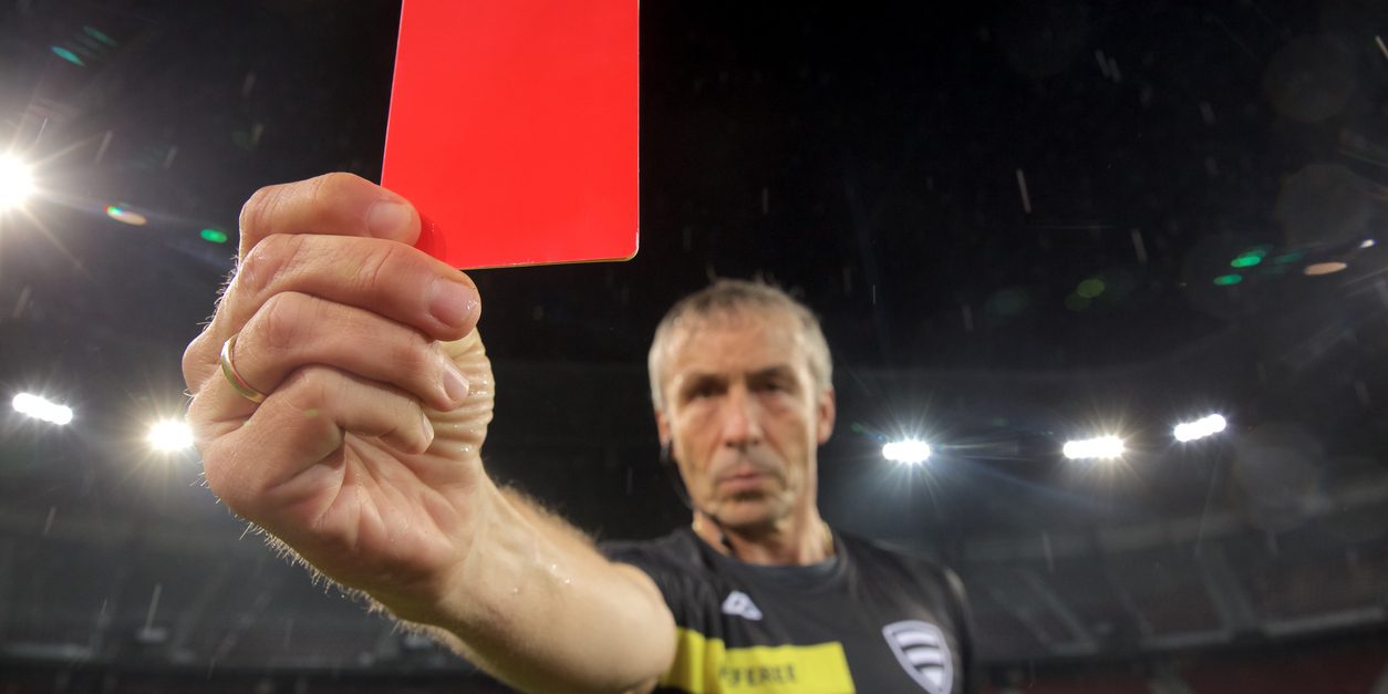 Portrait of referee showing red card during football match.