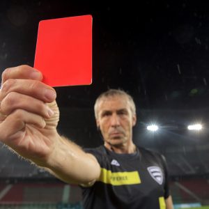 Portrait of referee showing red card during football match.