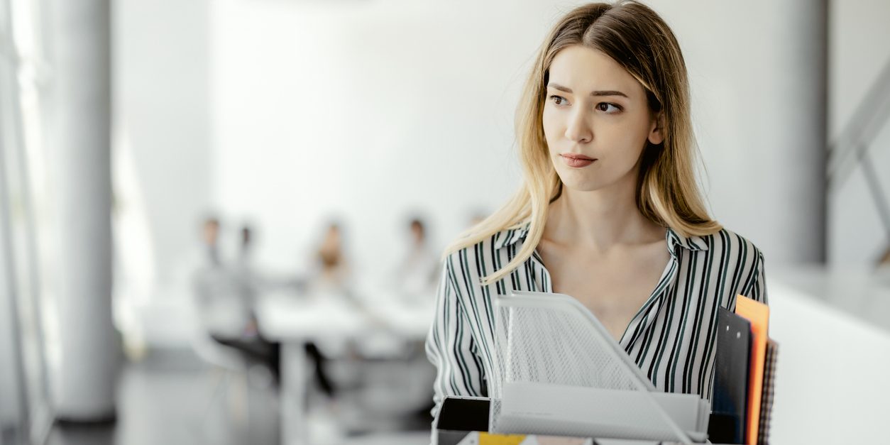 Upset businesswoman with cardboard box of things leaving office after being fired