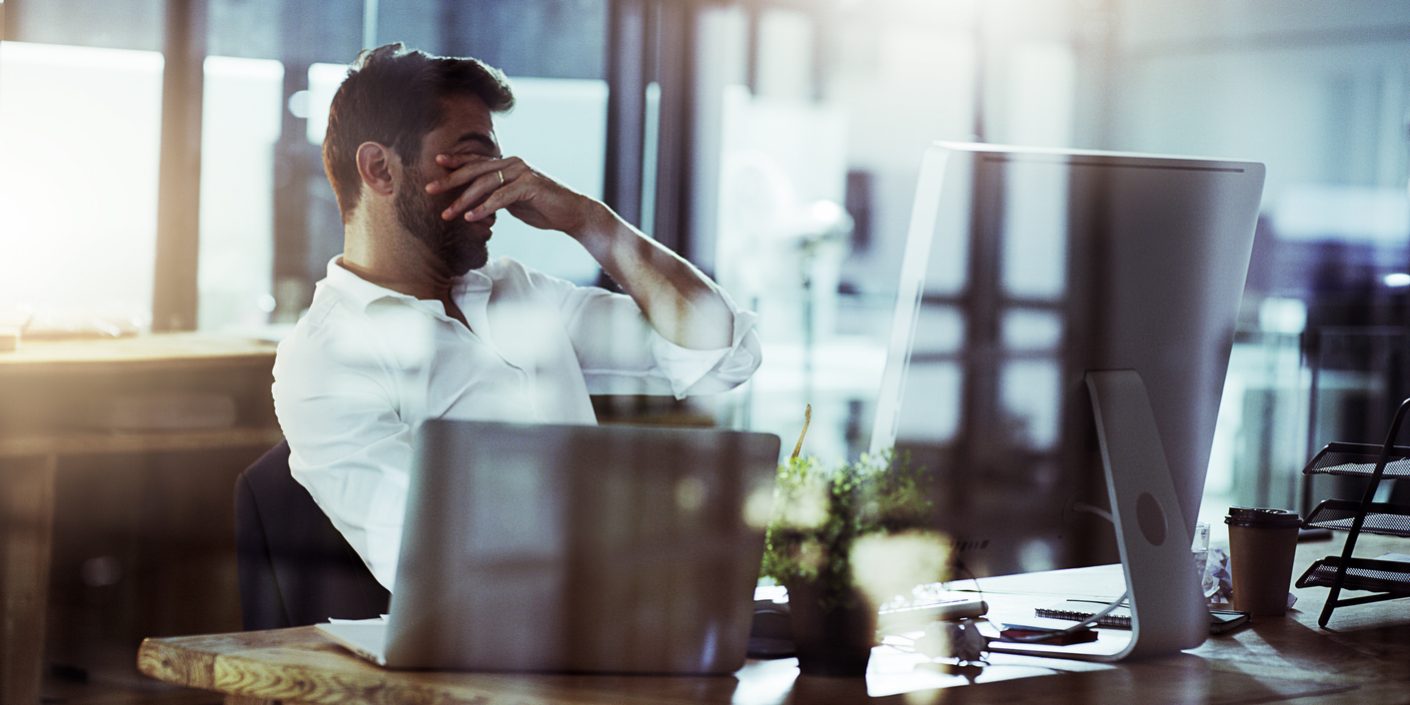 Cropped shot of a young businessman looking stressed while working late in the office