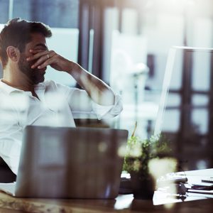 Cropped shot of a young businessman looking stressed while working late in the office