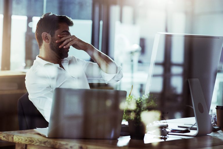 Cropped shot of a young businessman looking stressed while working late in the office