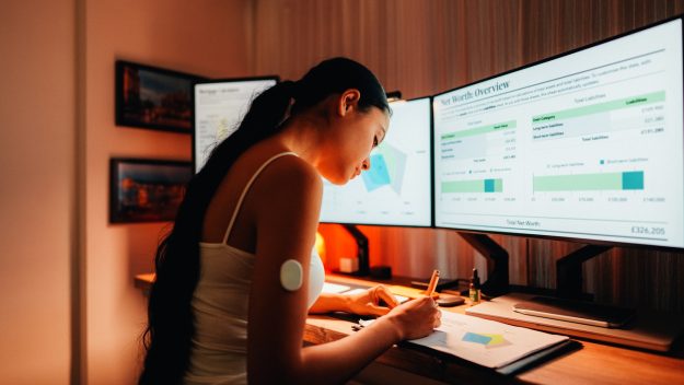 Woman is wearing small sensor on the back of upper arm for measuring glucose levels due to diabetes.