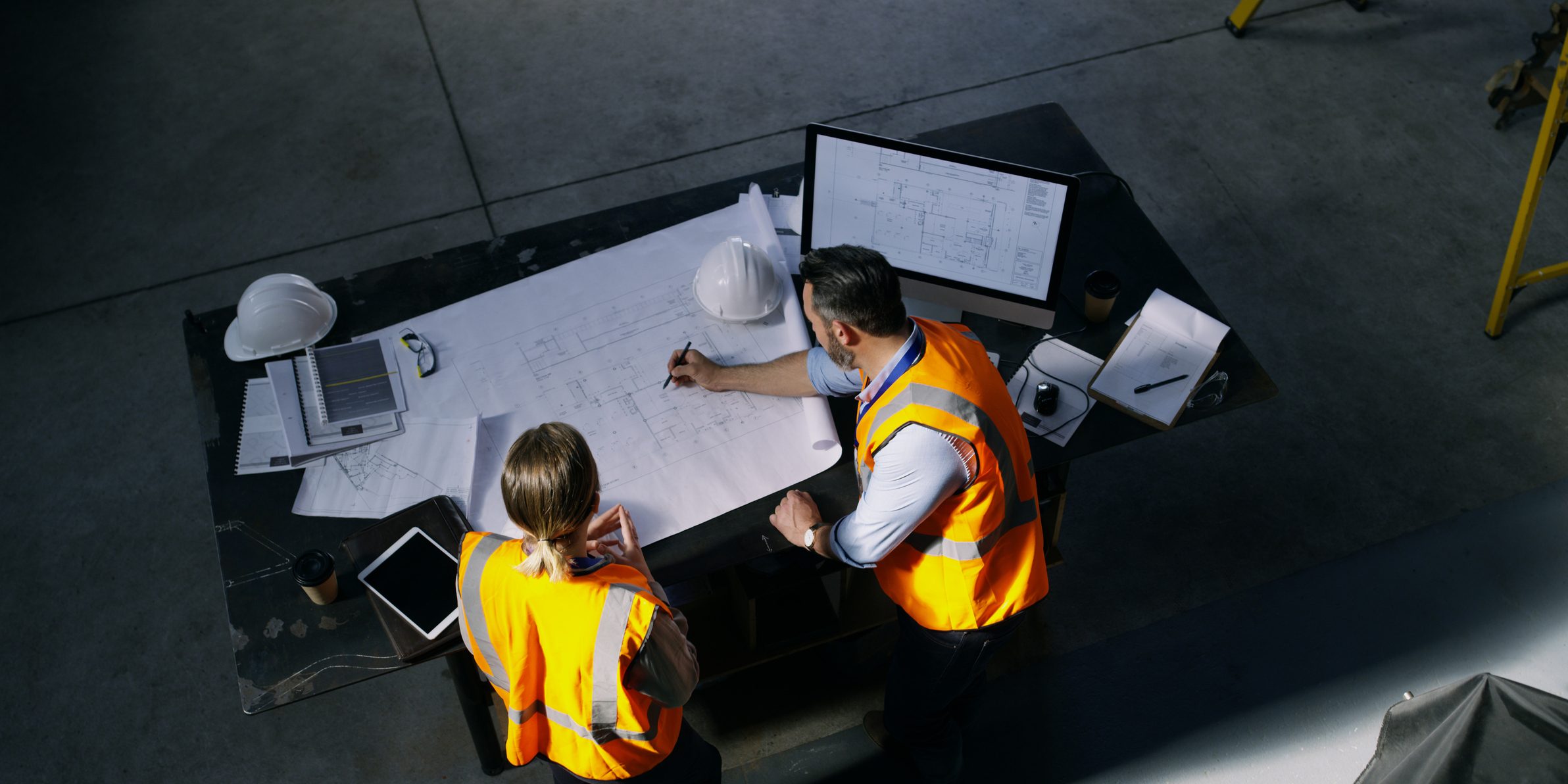 High angle shot of two engineers going over a blueprint together in an industrial place of work