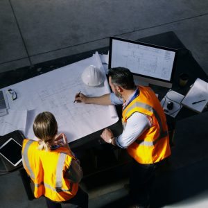 High angle shot of two engineers going over a blueprint together in an industrial place of work